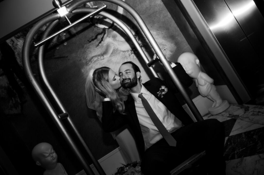 newly married couple in the lobby of the hotel kissing on a baggage cart